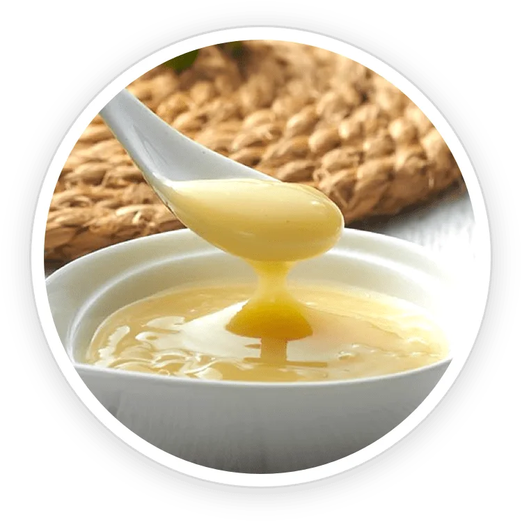 Royal jelly in a bowl with a wooden spoon